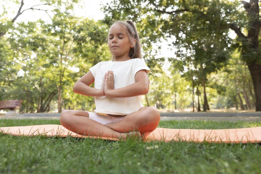 Niña practicando yoga en un parque